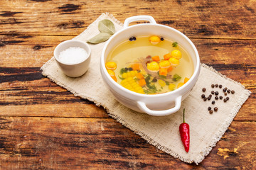 Transparent duck broth with dumplings and vegetables. Traditional bouillon, healthy food. Old wood background