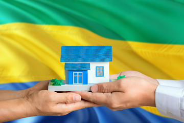 Gabon real estate concept. Man and woman holding miniature house in hands. Citizenship theme and...