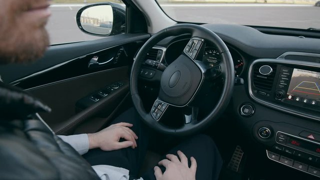 Self-driving autonomous car is parking by itself. The wheel is automatically revolving in a car cab