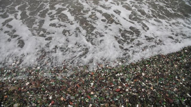 The famous beach with glass fragments stones in Russky Island, Vladivostok. Waves come to land. Environmental pollution
