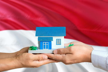 Indonesia real estate concept. Man and woman holding miniature house in hands. Citizenship theme...