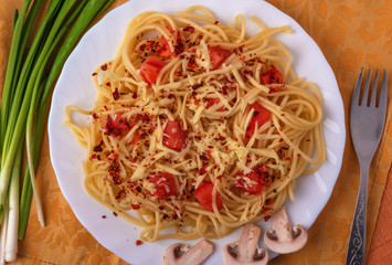 Dish for the restaurant menu, namely pasta with grated cheese and tomatoes with slices of mushrooms and spices in a design of green onions.