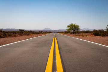 Lines of a deserted route in perspective. Car approaching far away.