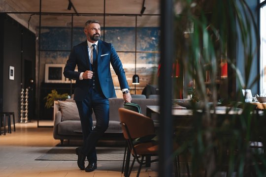 Stylish Bearded Man In A Suit Standing In Modern Office