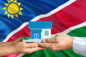 Namibia real estate concept. Man and woman holding miniature house in hands. Citizenship theme and...
