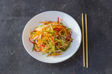 Asian style vegan salad bowl with vegetable mix on a dark background top view