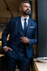 Stylish bearded man in a suit standing in modern office