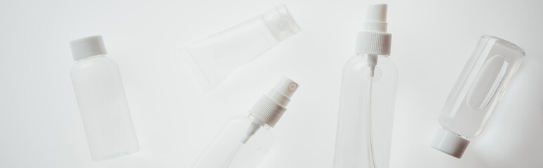 panoramic shot of white bottles with liquids ob white background