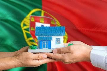 Portugal real estate concept. Man and woman holding miniature house in hands. Citizenship theme and...