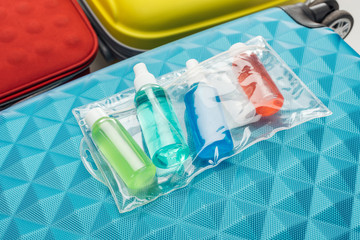 bright bottles with liquids and cosmetic bag on travel bag