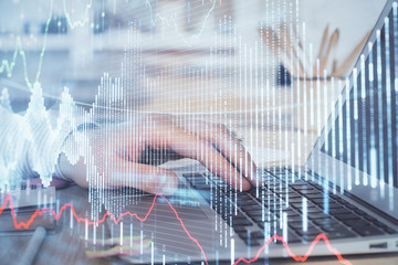 Double exposure of businessman's hands with laptop and stock market graph background. Concept of research and trading.