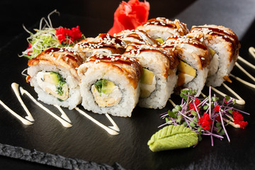 Sushi Rolls with cucumber, avocado, eel, omelet and Cream Cheese inside on black slate isolated. Philadelphia unagi roll sushi with tamago. Sushi menu. Horizontal photo.