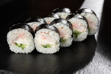 Sushi Rolls with shrimp, cucumber and Cream Cheese inside. Maki Futomaki Sushi Rolls with shrimp on black background. Sushi menu. Japanese food. Horizontal photo.