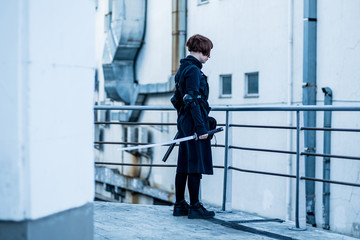 portrait of young redhead woman with japanese sword dressed in futuristic cyberpunk costume standing on the roof. 