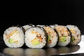 Sushi Rolls with eel, avocado, omelet and Cream Cheese inside. Maki Futomaki Sushi Rolls with eel on black background. Sushi menu. Japanese food. Horizontal photo.