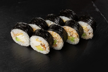 Sushi Rolls with eel, avocado, omelet and Cream Cheese inside. Maki Futomaki Sushi Rolls with eel on black background. Sushi menu. Japanese food. Horizontal photo.