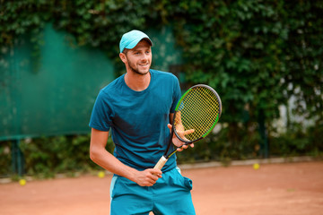 Portrait of a handsome tennis player holding a racket.