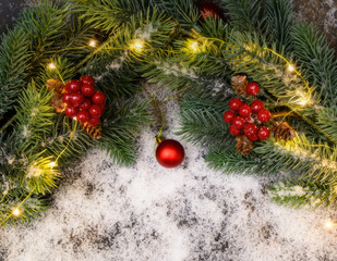 Christmas background with fir twigs, red berries, cones and Xmas lights on snow background with plenty of text space