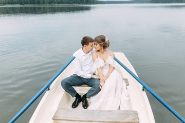  Stylish wedding in European style. Happy couple on a boat on the lake.