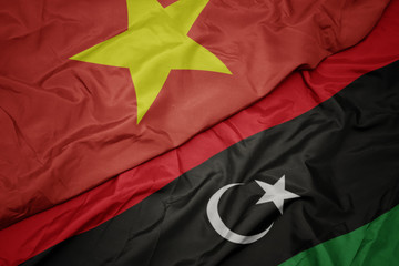 waving colorful flag of libya and national flag of vietnam.