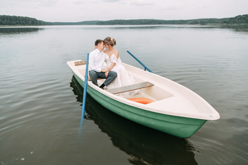 Fototapeta na wymiar Stylish wedding in European style. Happy couple on a boat on the lake.