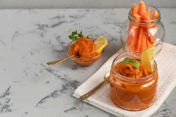 Carrot jam with orange juice, decorated with mint and slices of lemon on a pineapple, stone background. Autumn product. The horizontal location. Copy space.  