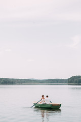 Fototapeta na wymiar Stylish wedding in European style. Happy couple on a boat on the lake.