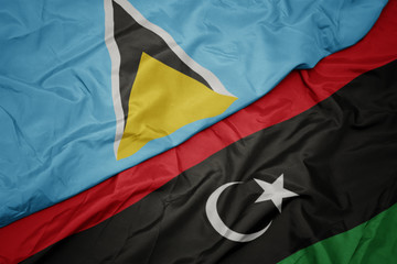 waving colorful flag of libya and national flag of saint lucia.