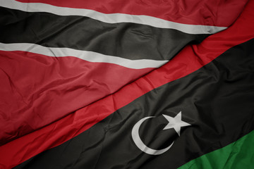 waving colorful flag of libya and national flag of trinidad and tobago.