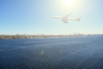 Fototapeta na wymiar The plane over the river and the city. The sun shines.