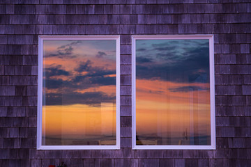 The sun reflects itself in the windows of beachfront homes in the pacifi coast; beautiful, dramatic skies and colors; golden light. Artistic editing and outtake.