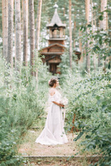 Fototapeta premium Elegant ceremony in European style. Beautiful bride in white flying dress in the forest.