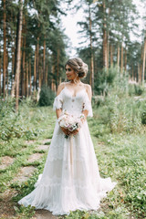 Fototapeta na wymiar Elegant ceremony in European style. Beautiful bride in white flying dress in the forest.