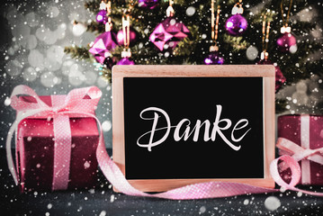 Obraz na płótnie Canvas Blackboard With German Calligraphy Danke Means Thank You. Christmas Tree With Purple Ball Ornament And Pink Gift. Bokeh Effect With Snowflakes
