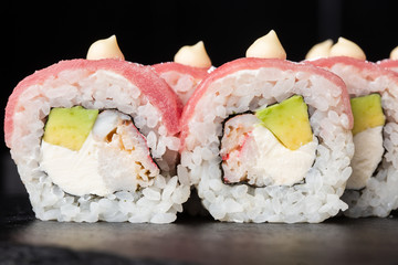 Sushi Rolls with avocado,tuna, shrimp, crab meat and Cream Cheese inside on black slate isolated. Philadelphia roll sushi with tuna. Sushi menu. Horizontal photo.