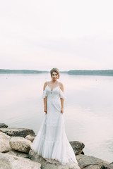 Fototapeta na wymiar Wedding dress in European style. Happy bride at sunset on the lake.