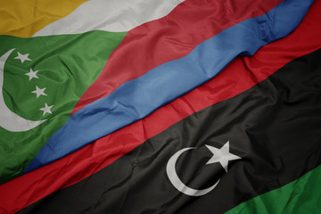 waving colorful flag of libya and national flag of comoros.
