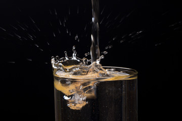 Gotas de agua chapoteando y salpicando un recipiente de cristal o plástico transparente