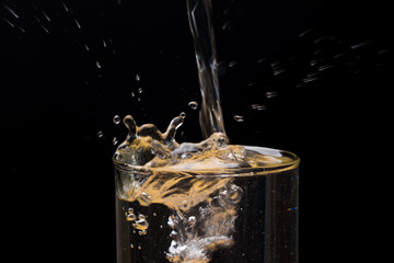 Gotas de agua chapoteando y salpicando un recipiente de cristal o plástico transparente