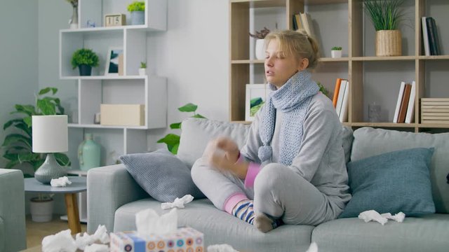 Girl blows her nose in a napkin on sofa