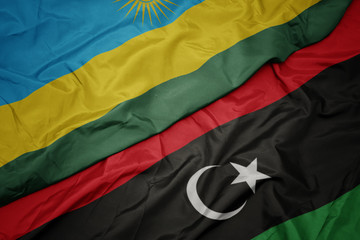 waving colorful flag of libya and national flag of rwanda.