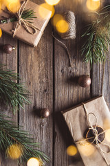 Christmas gifts for new year wrapped in craft paper near branches and cones on wooden background