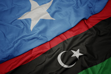 waving colorful flag of libya and national flag of somalia.