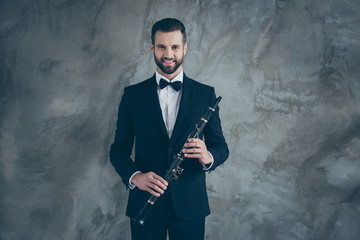 Photo of cheerful positive fun professional musician in suit holding clarinet before playing smiling toothily isolated grey color concrete wall background