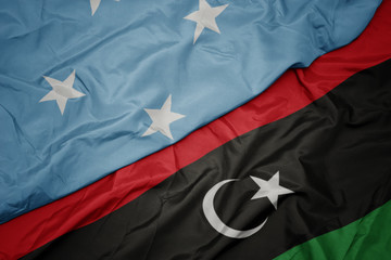 waving colorful flag of libya and national flag of Federated States of Micronesia .