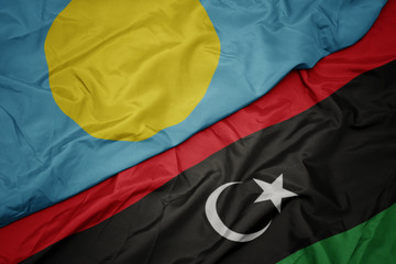waving colorful flag of libya and national flag of Palau .