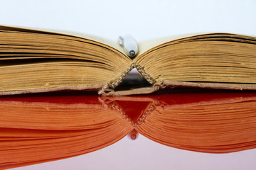 An opened old yellowed book and a fountain pen on a light mirror background. Library archive. History and modernity. Educational and fiction