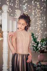 girl in elegant dress by the christmas tree