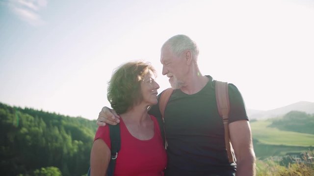 Senior tourist couple travellers hiking in nature, kissing. Slow motion.