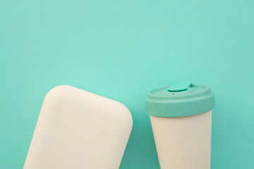 Reusable stylish eco friendly bamboo cup and lunch box on light blue background.